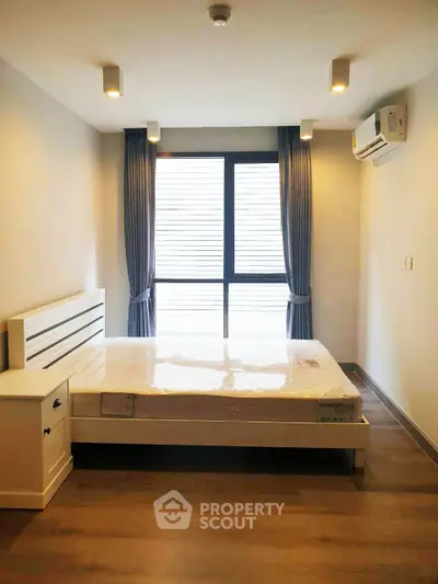 Modern bedroom with large window and air conditioning in a stylish apartment.