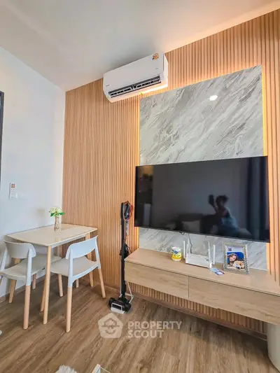 Modern living room with stylish decor, featuring a mounted TV, sleek dining set, and elegant wood paneling.