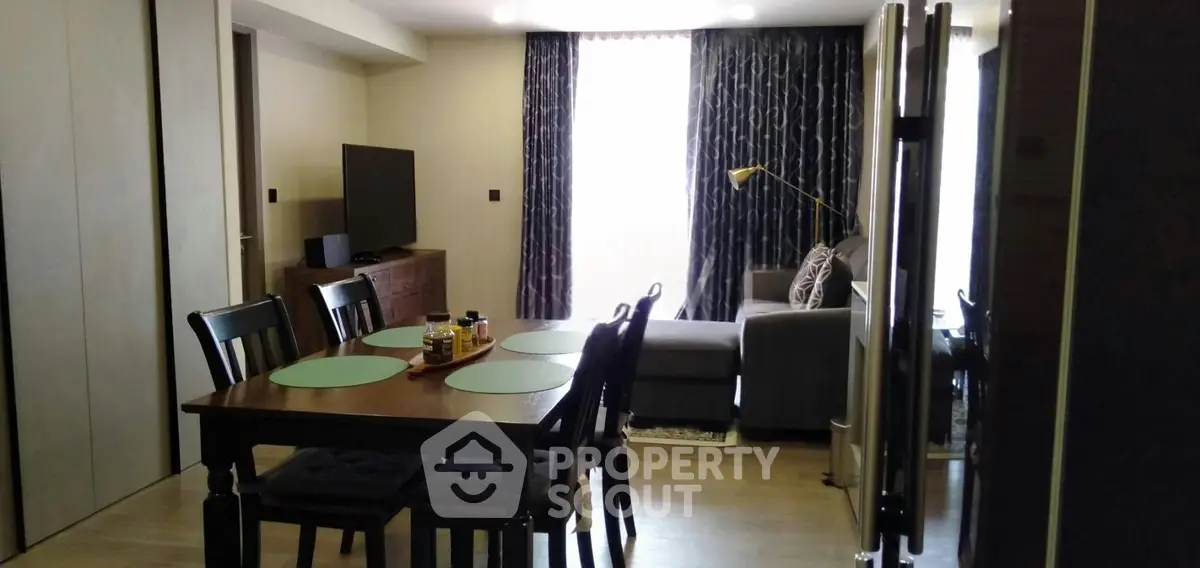 Modern living room with dining area, featuring elegant furniture and natural light.