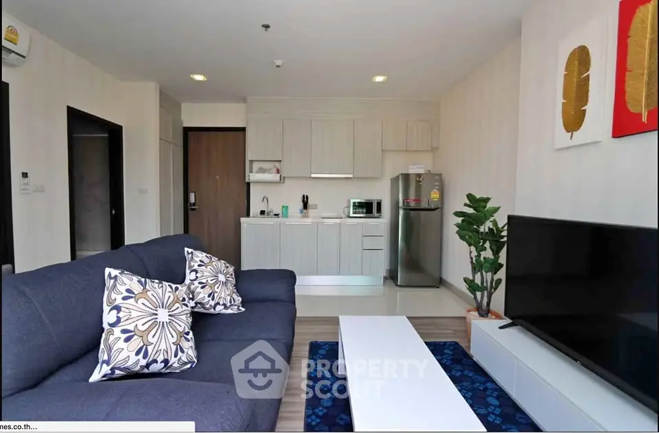 Modern living room with open kitchen, stylish decor, and cozy seating area.