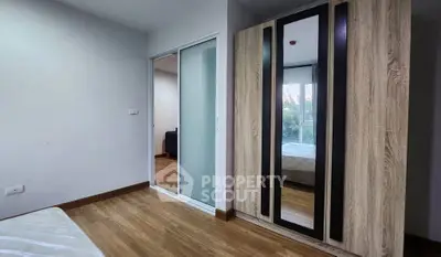 Modern bedroom with wooden flooring and mirrored wardrobe