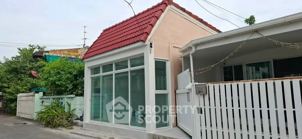 Charming small house with red roof and large windows in a quiet neighborhood.