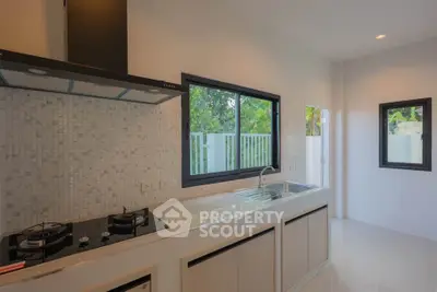 Modern kitchen with sleek design, featuring gas stove and large windows for natural light.