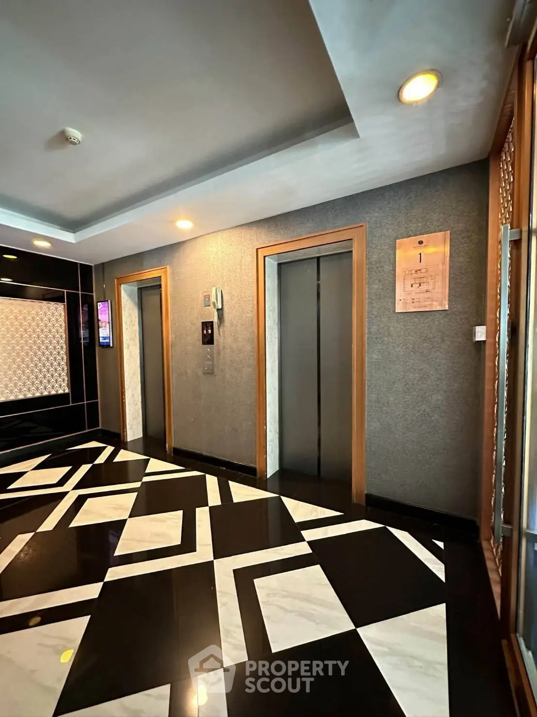 Modern building lobby with stylish elevators and geometric floor design.
