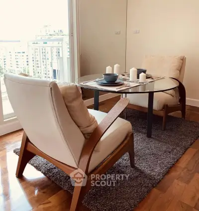 Chic living room with modern armchairs and glass table, offering a cozy ambiance and city view.