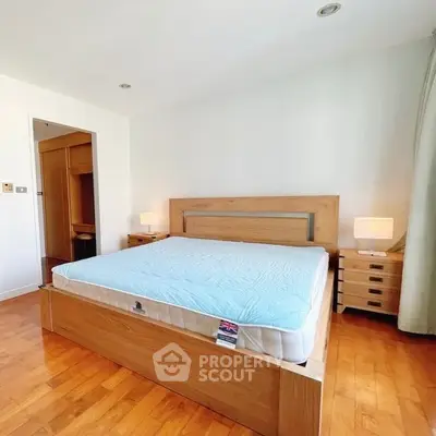 Spacious bedroom with wooden flooring and modern furniture