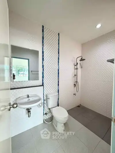 Modern bathroom with sleek design, featuring a shower area and contemporary fixtures.