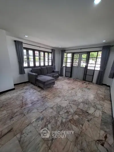 Spacious living room with marble flooring and large windows offering natural light.