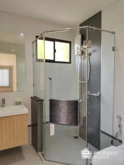 Modern bathroom with glass-enclosed shower, sleek fixtures, and natural light filtering through frosted windows, complemented by neutral tones and clean lines.