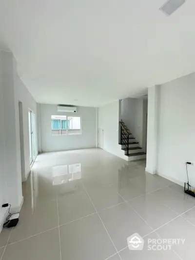 Spacious modern living room with glossy tile flooring and staircase