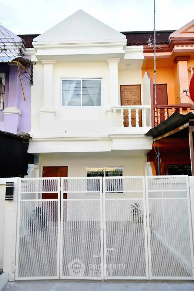 Charming two-story townhouse with gated entrance and colorful facade in a vibrant neighborhood.