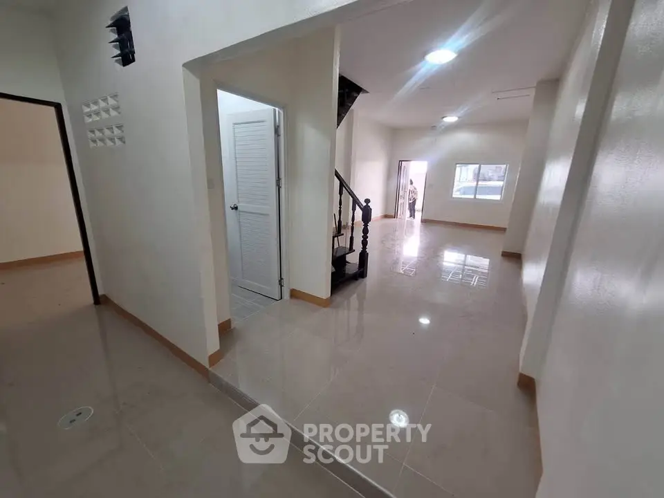 Spacious open-plan interior with glossy tiled floors and staircase, ideal for modern living.