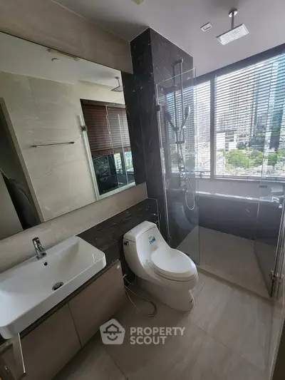 Modern bathroom with city view, glass shower, and sleek fixtures in urban apartment.