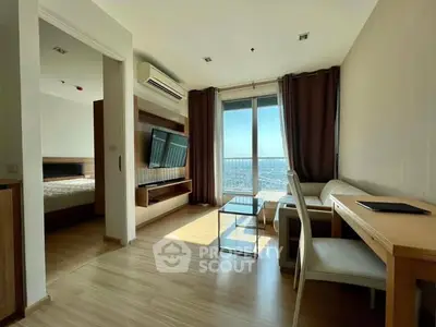 Modern living room with wooden flooring, large window, and city view.
