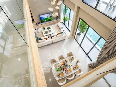 Luxurious open-plan living and dining area with pool view, featuring modern decor and high ceilings.