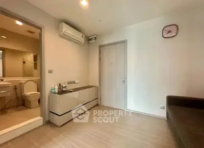 Modern living room with air conditioning and bathroom access, featuring sleek flooring and minimalist decor.