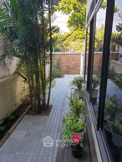 Charming garden patio with lush greenery and potted plants, perfect for relaxation.