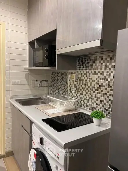 Modern compact kitchen with sleek cabinetry, mosaic backsplash, and built-in appliances for efficient living.