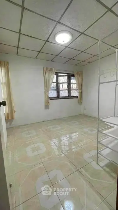 Spacious empty room with tiled floor and large window, perfect for customization.