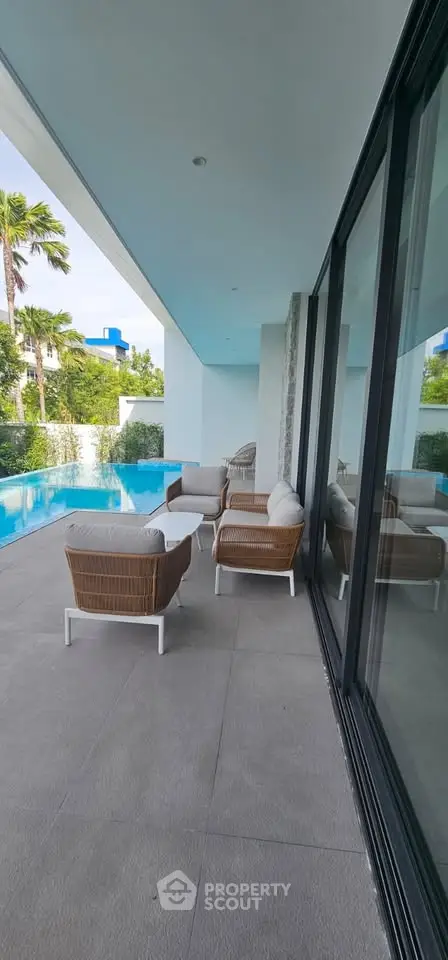 Luxurious poolside patio with modern outdoor furniture and lush greenery.