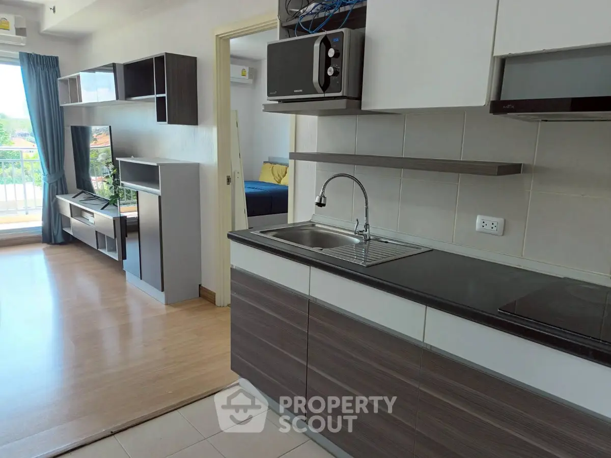 Modern open-layout kitchen with sleek cabinetry and adjacent living area, featuring a balcony view.