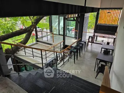 Modern industrial-style cafe with large windows and outdoor seating area.