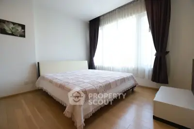 Bright and cozy bedroom with large window and elegant curtains, perfect for relaxation.