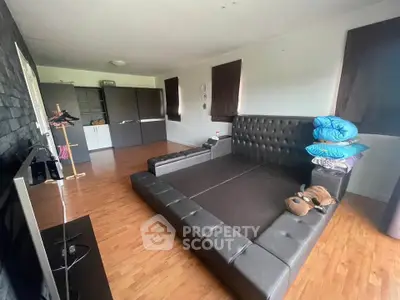 Spacious living room with modern black leather seating and wooden flooring