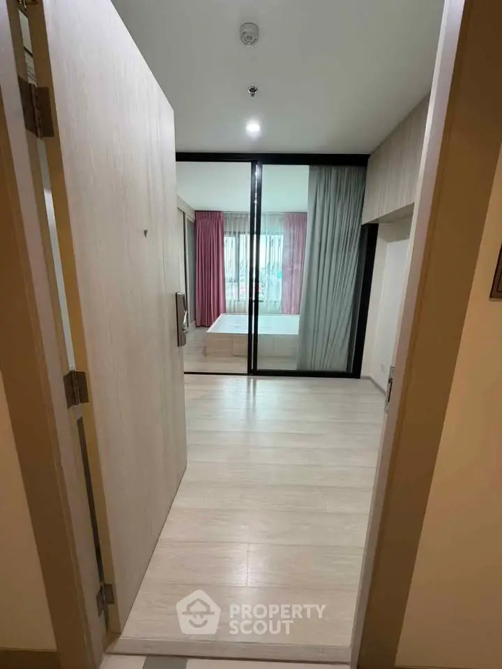 Modern apartment entrance leading to a stylish bedroom with large windows and elegant curtains.