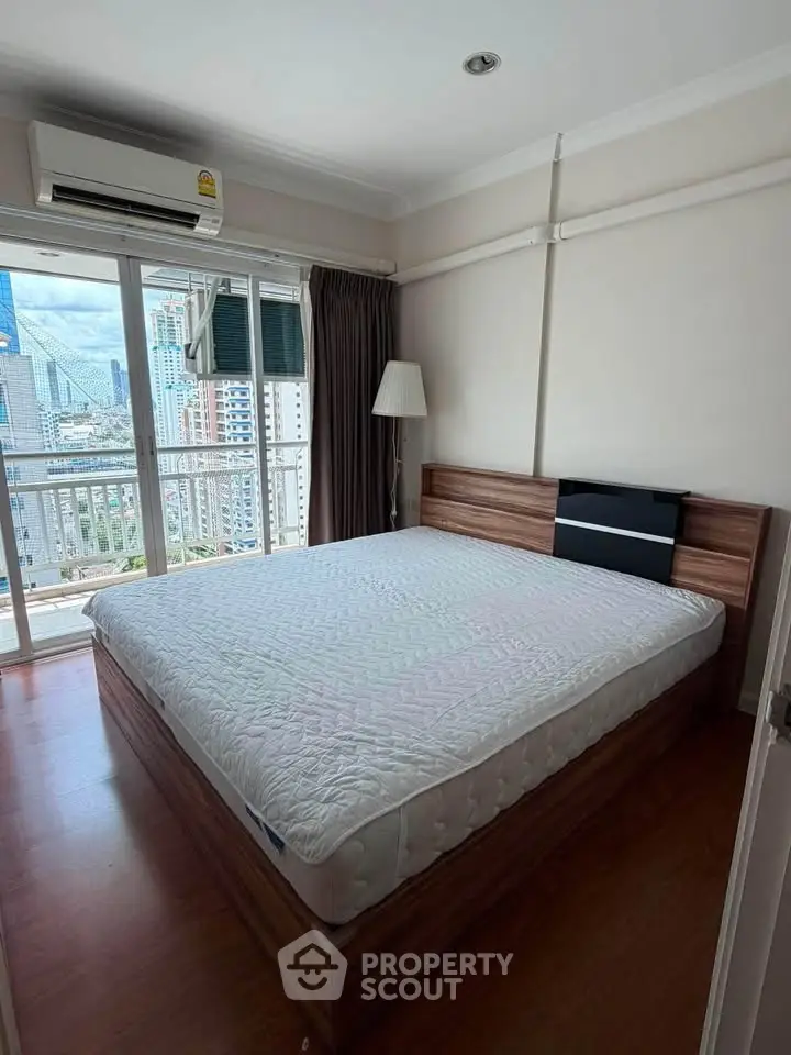 Spacious bedroom with city view and large window in modern apartment