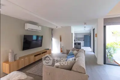 Modern living room with stylish decor and open layout leading to kitchen and garden view.