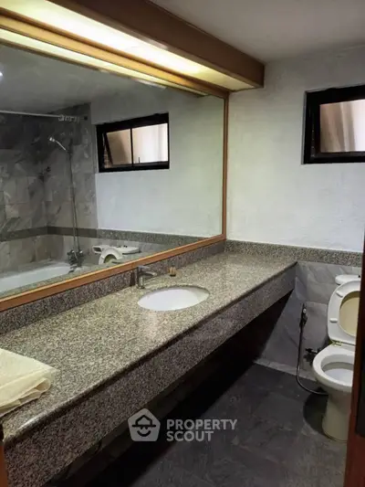 Spacious bathroom with granite countertop and bathtub in modern home