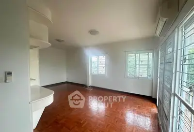 Spacious empty living room with wooden flooring and large windows in a modern home.