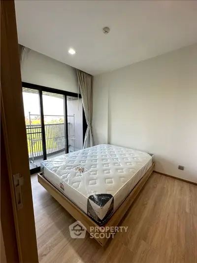 Spacious bedroom with natural light, pristine wooden flooring, and direct balcony access, ready for personalization in a modern home.