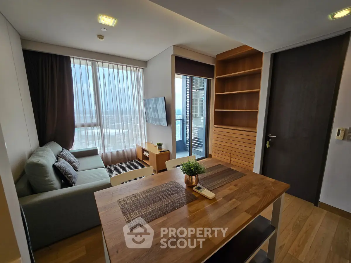 Modern living room with large windows and stylish furniture, featuring a cozy sofa and a wooden dining table.