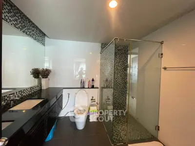Modern bathroom with glass shower and sleek black countertop