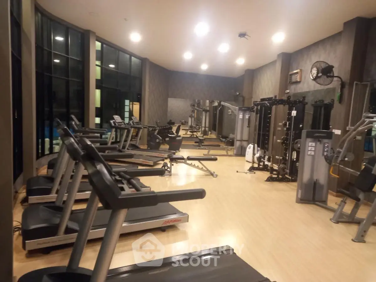 Spacious modern gym with state-of-the-art equipment and large windows for natural light.