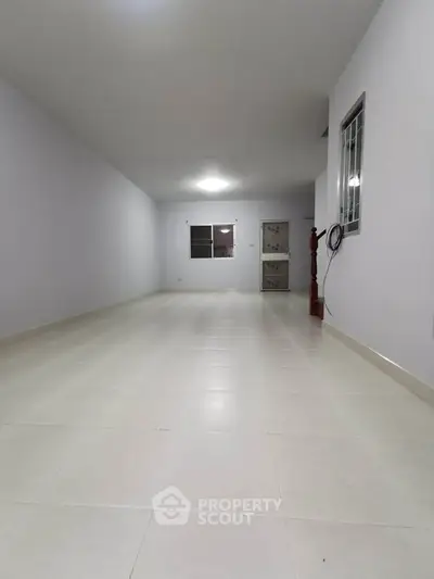 Spacious empty room with tiled flooring and white walls, ideal for customization.