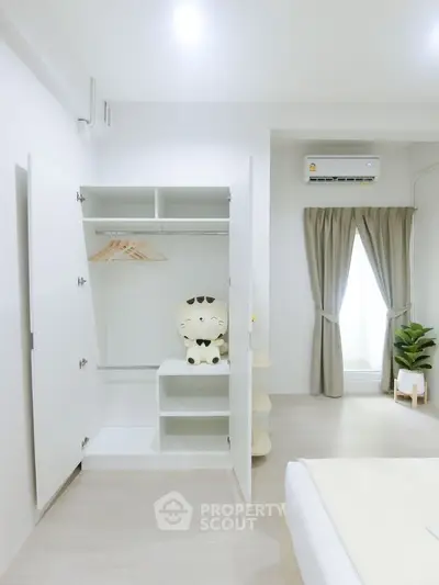 Bright bedroom with open wardrobe and air conditioning, showcasing modern minimalist design.