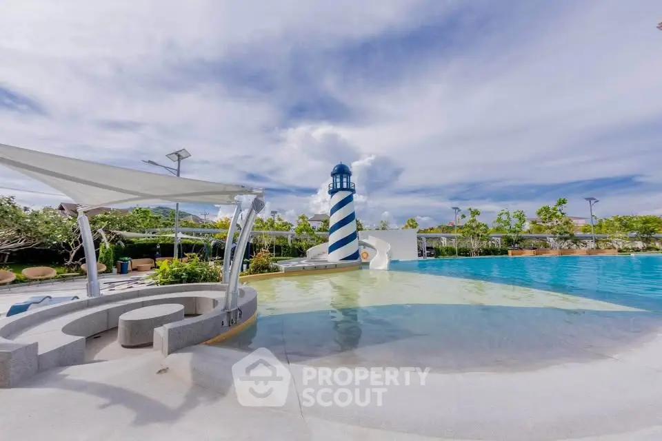 Luxurious pool area with lighthouse slide and modern seating under blue sky.