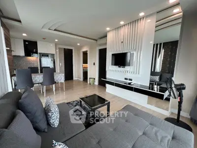 Modern living room with sleek design, featuring a stylish sofa, wall-mounted TV, and elegant dining area.