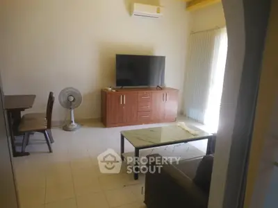 Cozy living room with modern TV setup and air conditioning, perfect for relaxation.