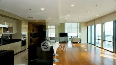 Spacious modern living room with open kitchen and large windows offering city views.