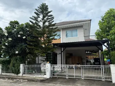 Charming two-story house with lush garden and spacious driveway in a serene neighborhood.