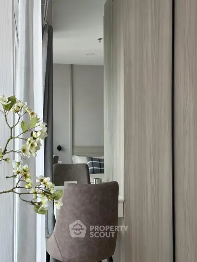 Modern bedroom with stylish chair and floral decor, featuring sleek wooden wardrobe.