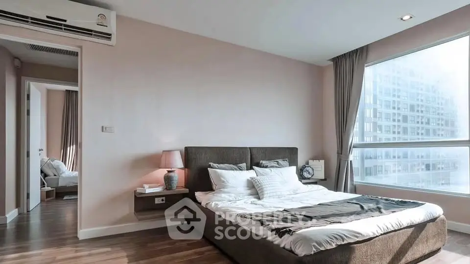 Modern bedroom with large window and stylish decor in a high-rise apartment.
