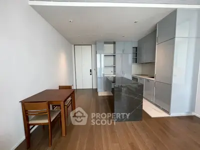 Modern kitchen with sleek cabinetry and dining area in open layout apartment.