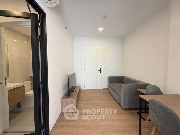 Modern living room with sleek furniture and wooden flooring, featuring a cozy sofa and a flat-screen TV.