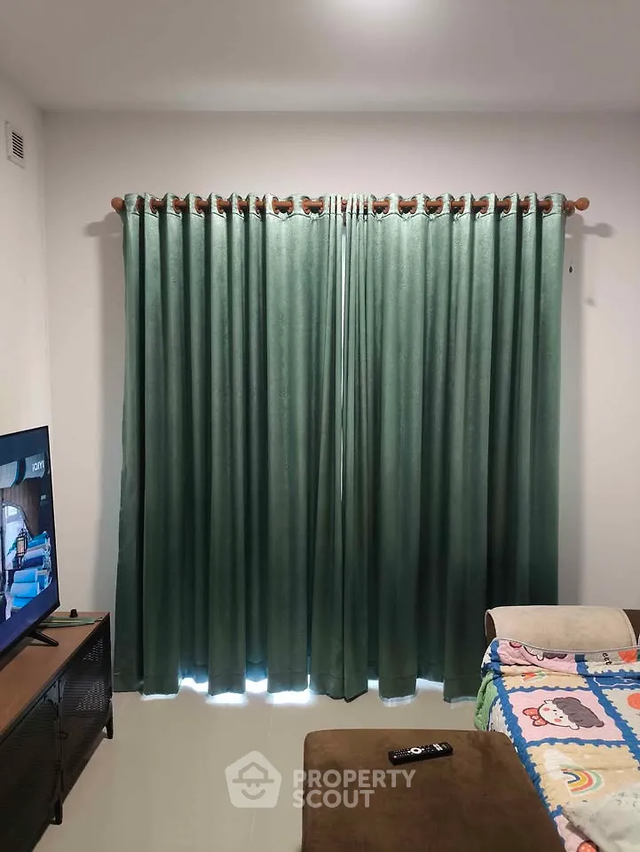 Cozy living room with green curtains and TV setup, perfect for relaxation.