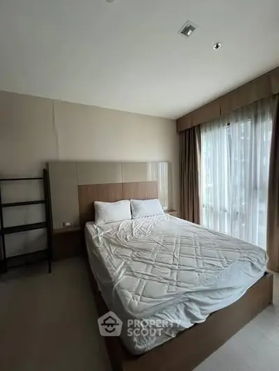 Spacious bedroom with natural light and modern furnishings in a stylish apartment.